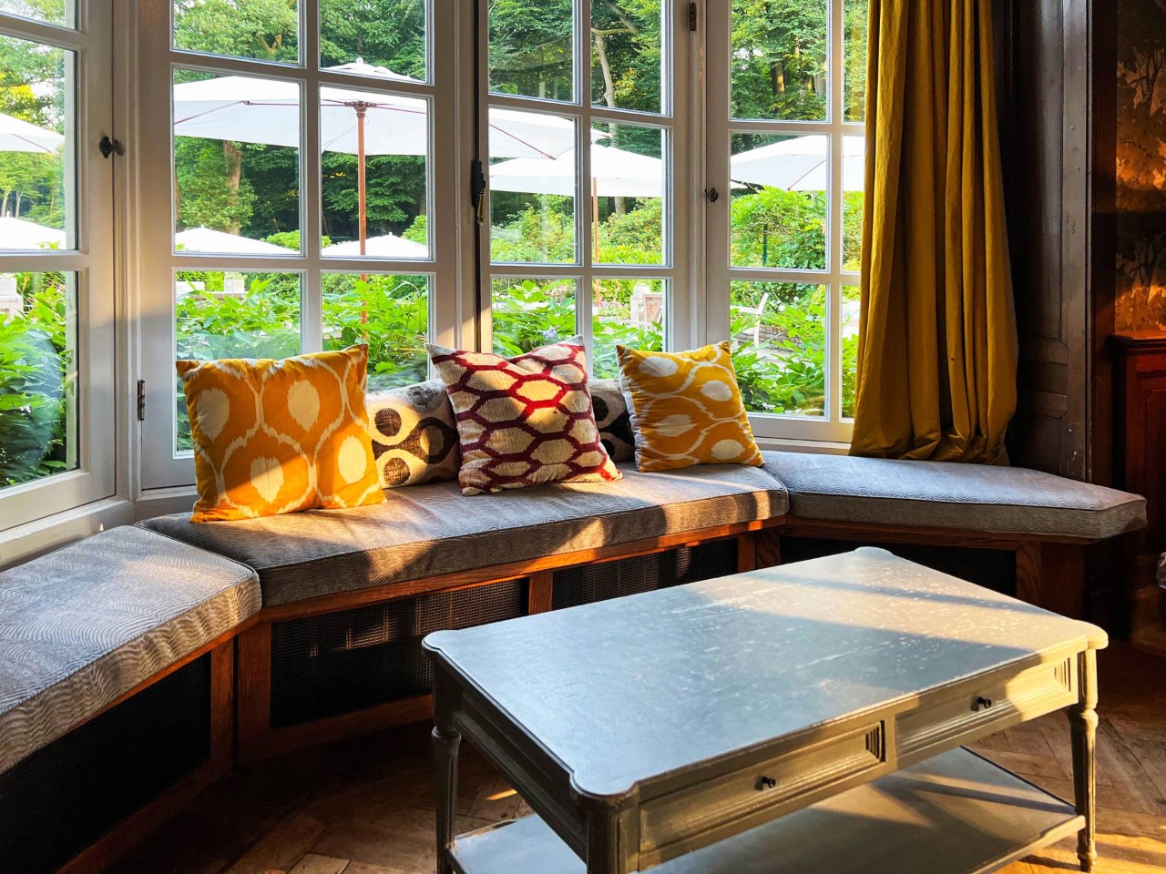 A bay window space with bench seating, a small table, and curtains at Bell's Ethan Allen Design Center near Newburgh, NY